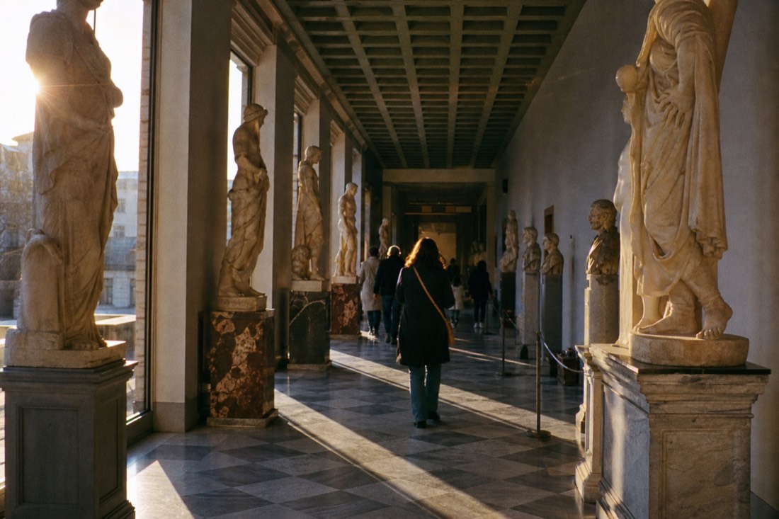 The facade of the Palazzo Vecchio in Florence with a white marble replica statue beside the arched doorway under evening light
