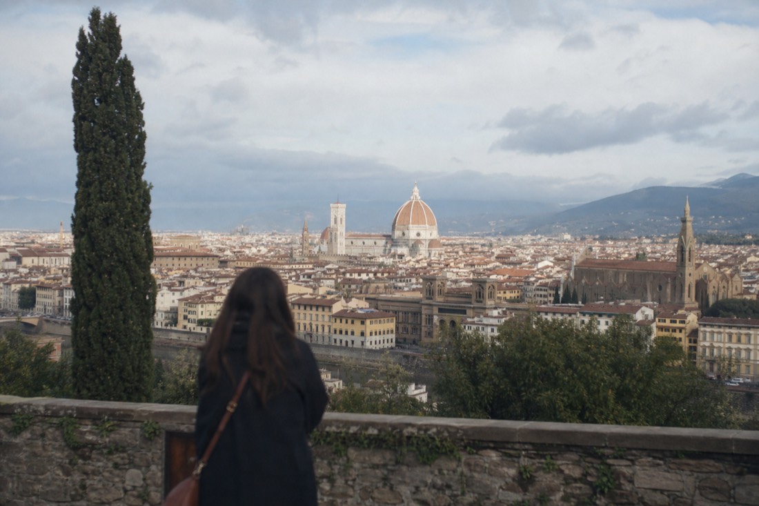Rooftops and the dome of Florence seen across the city in warm late afternoon light with a stone bell tower