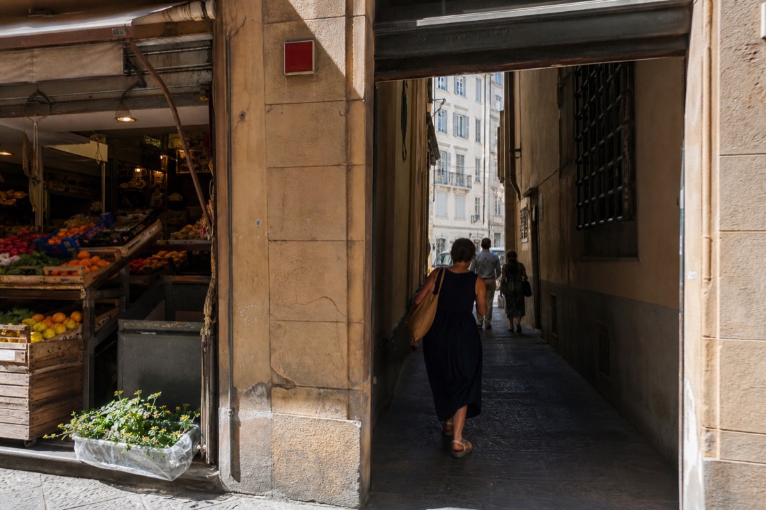 Narrow Florence street doorway with a red street number tile beside a small grocery storefront