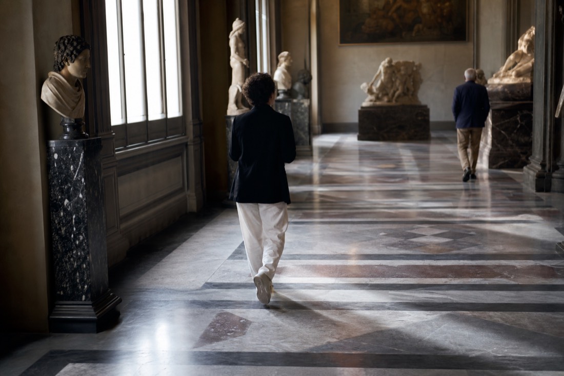 Sunlight streaming through tall windows onto the marble floor of a nearly empty Accademia Gallery hall in early morning