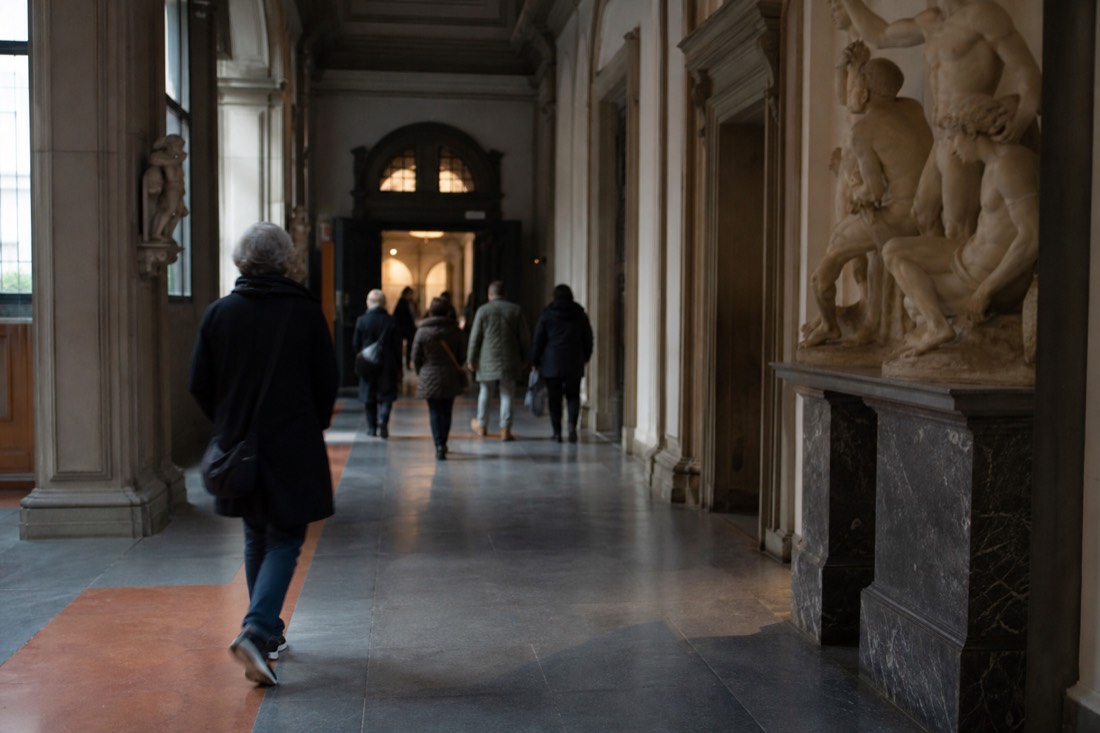 Morning shadows stretching across the stone pavement outside the Accademia Gallery entrance on a quiet Florence street