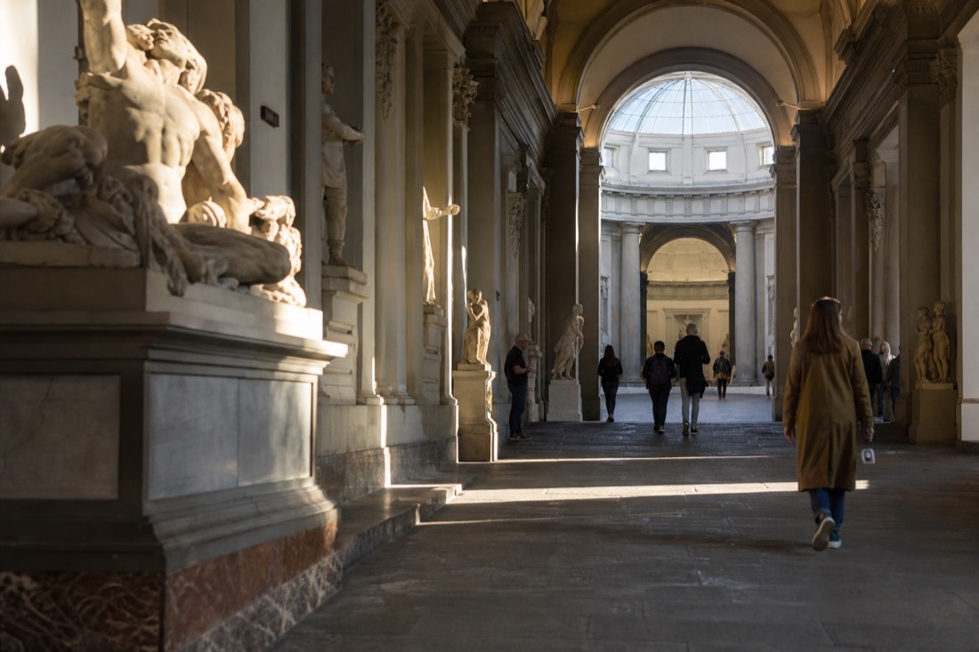 Sculptures lining the skylit corridor of the Accademia Gallery leading the eye toward the domed tribune in Florence