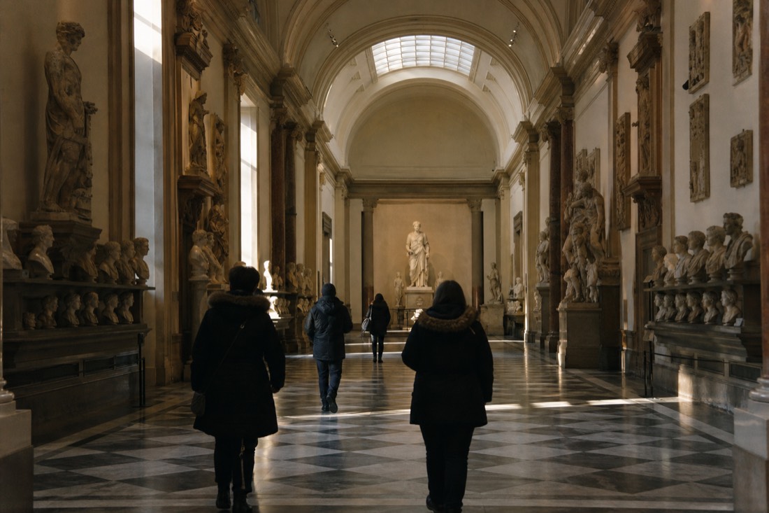 First visitors of the morning walking down the long sculpture hall of the Accademia toward David under the skylight