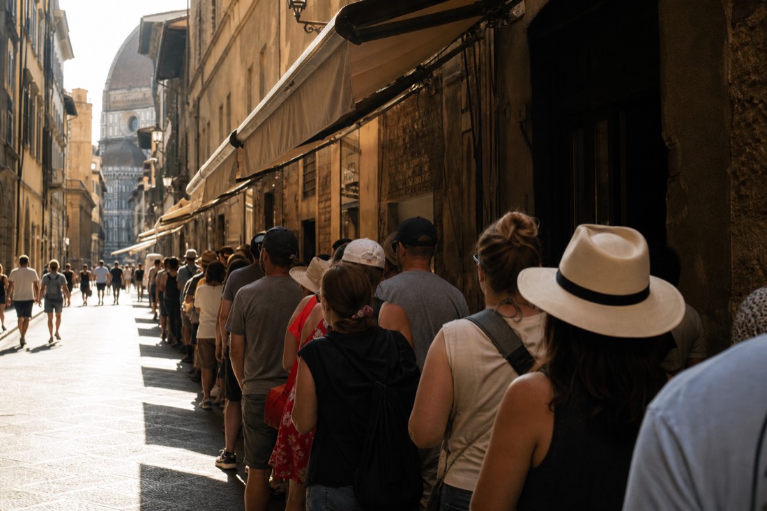 Long shaded queue of summer visitors waiting along a narrow Florence street with rolled awnings overhead